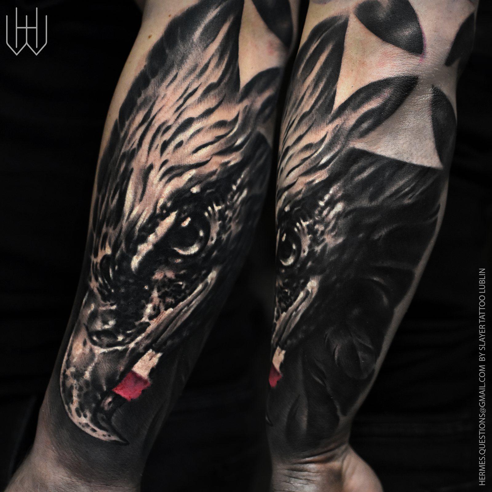 Tatuaż realistyczny czarno-szary — głowa ptaka drapieżnego z motywem blackwork na przedramieniu, Hermes.art.tattoo Lublin